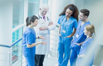 Bildet viser sykepleiere og en lege som snakker sammen i korridoren