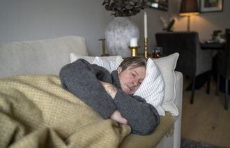 Bildet viser syk mann på sofa