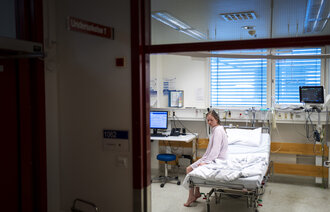Bildet viser en pasient som sitter i en sykehusseng