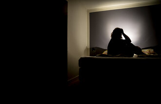 Illustrasjon av en person som sitter i mørket og har det vondt