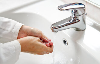 The image shows a patient washing their hands at the sink