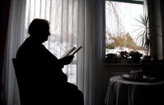 Bilde av eldre person ved kjøkkenbordet