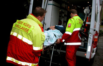Bildet viser en mann som blir hentet av ambulansepersonale, og ligger på båre.