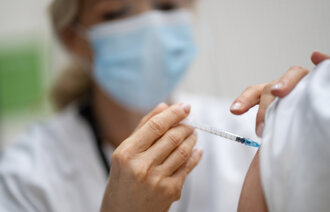 Bildet viser helsepersonell som setter en vaksine.