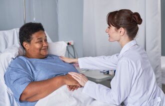 Bildet viser en sykepleier som trøster en pasient i sykehussengen