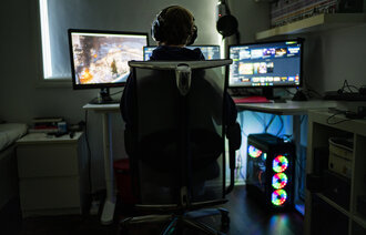 Bildet viser en gutt som gamer alene på gutterommet.