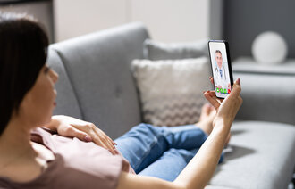 Bilde av person på sofa med mobiltelefon
