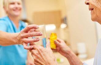 Pasient får medikamenter av pleier.