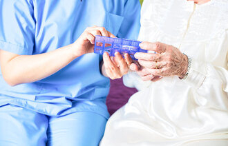 Bildet viser en sykepleier som viser en pasient en medisindosett