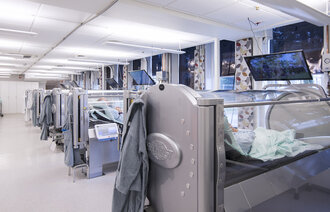 Bildet viser flere trykkamre på rekke og rad, der folk behandles for blant annet stråleskader