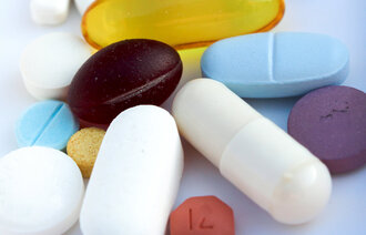En håndfull piller i hvitt, blått, gult og rosa strødd utover.