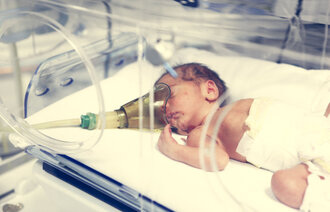 Bildet viser en nyfødt som ligger i en kuvøse.