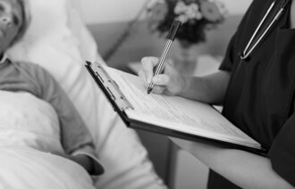 Helsepersonell fyller ut skjema ved sykehussengen