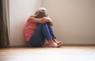 Bildet viser et barn som sitter i en krok og er tydelig lei seg.