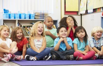 Flere barn som sitter på gulvet og ser ut til å kose seg