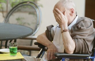 Bildet viser en eldre mann som holder seg til ansiktet i fortvilelse.