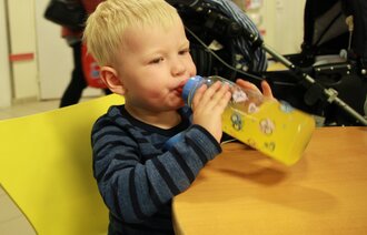 Sebastian drikker gul saft fra flaske.