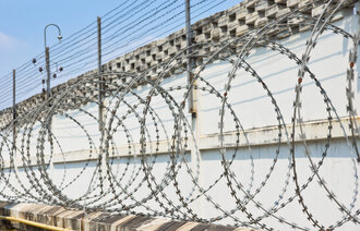Bilde av piggtråd og gjerde rundt et fengsel