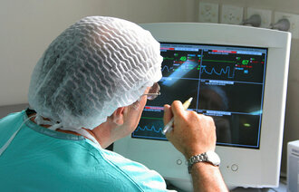 En kirurg sitter og vurderer pasientdata på en dataskjerm