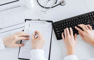 Bildet viser et par hender som fyller ut et skjema og et par hender som skriver på et tastatur