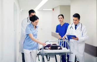 Bildet viser leger og sykepleiere rundt en kvinne som ligger på en båre