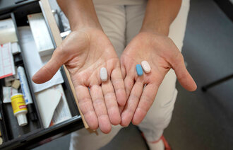 Bildet viser to hender som holder hiv-medisiner.
