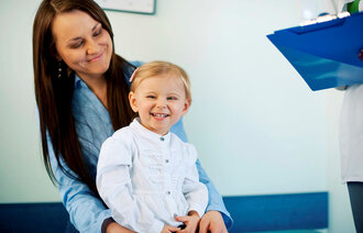 Mor og barn på sykehus. Helsepersonell gir informasjon.