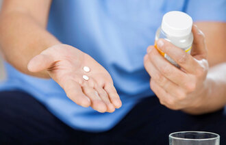 Sykepleier holder piller og pilleglass.