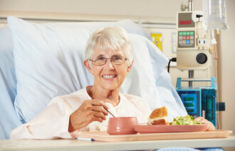 Pasient får mat servert i sykehusseng