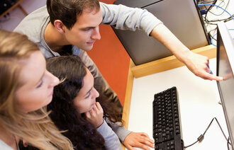 Tre unge mennesker ser på en pc.