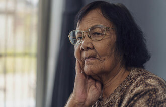 Bildet viser en eldre kvinne som ser ut i luften