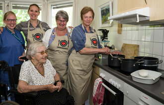 Bildet viser fem kvinner på kjøkkenet.