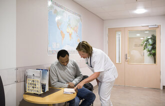 Bildet viser en sykepleier og en pasient på et venterom på en poliklinisk avdeling på Haukeland universitetssjukehus