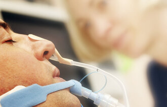 Bildet viser en intubert pasient med ernæringssonde.