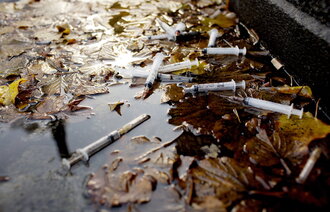 Bildet viser brukte sprøyter i en vannpytt.