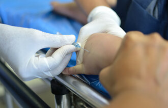 Bilde av en pasient som får lagt inn venekateter i hånden.