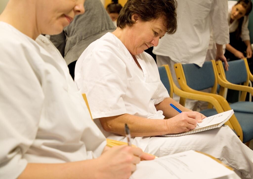 Bildet viser to sykepleiere som sitter og noterer