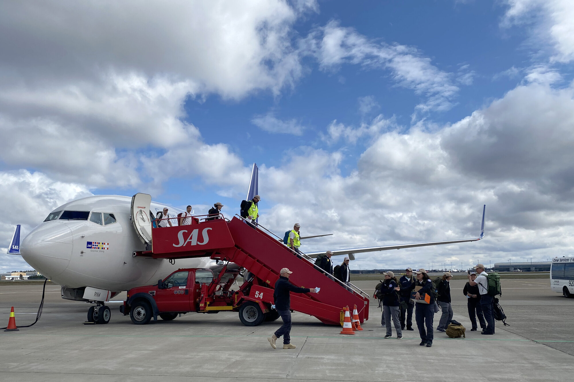 Bildet viser medisinsk innsatsteam på vei ut av et fly.