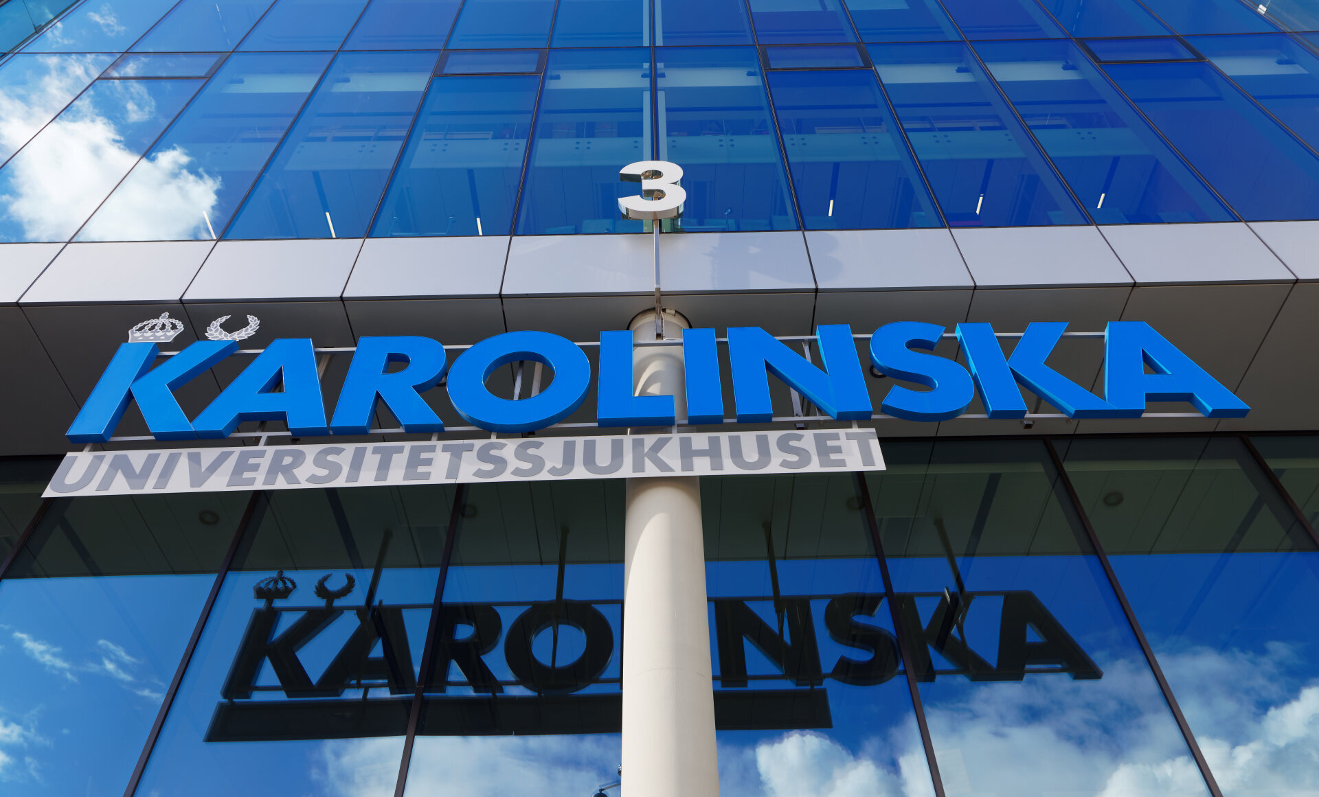 Bildet viser en bygning med et skilt der det står Karolinska i blå bokstaver.