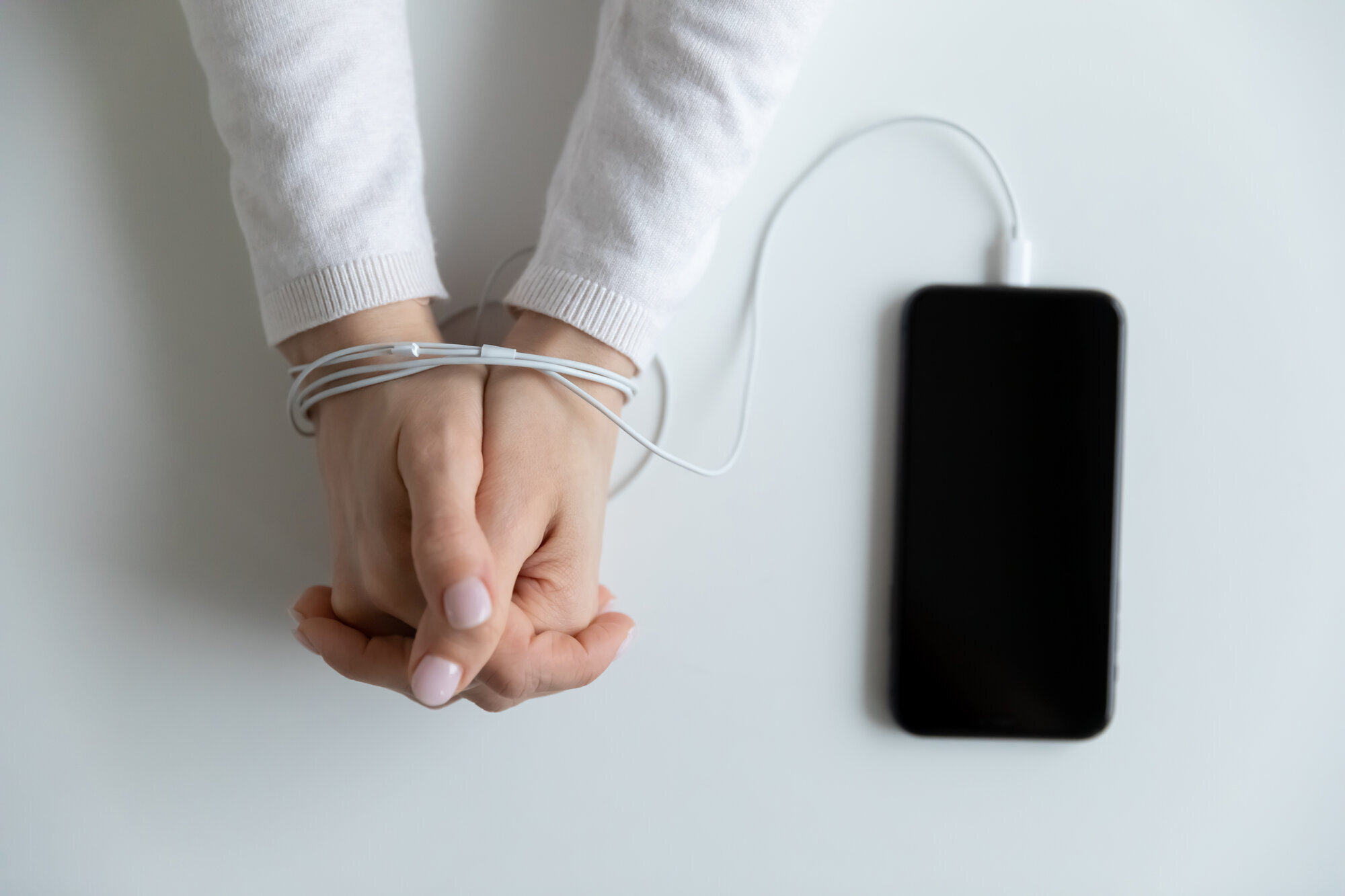 bildet viser et par hender som er bundet til mobilen