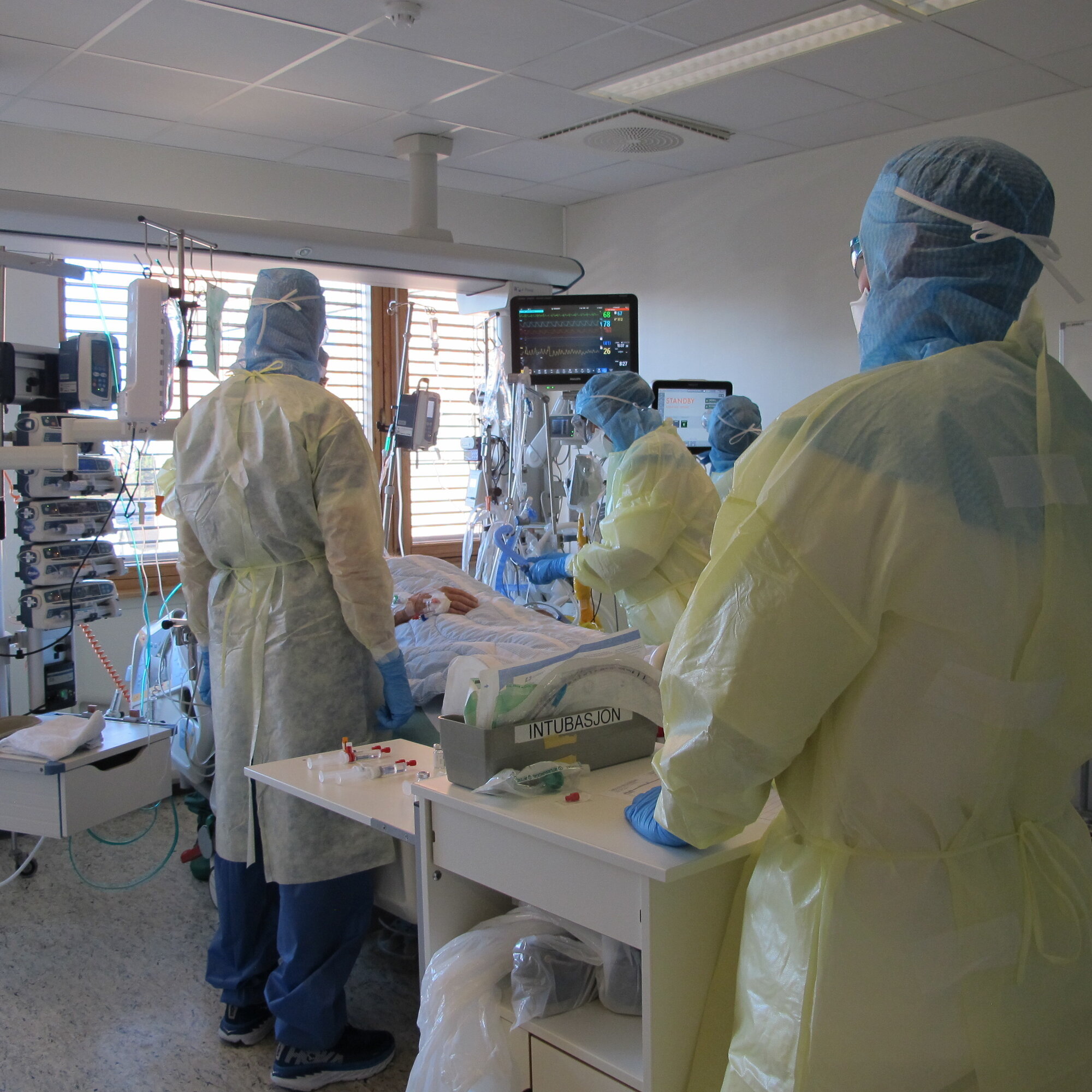 Bildet viser sykepleiere ved en pasient som er innlagt for covid-19, i en såkalt covid-kohort