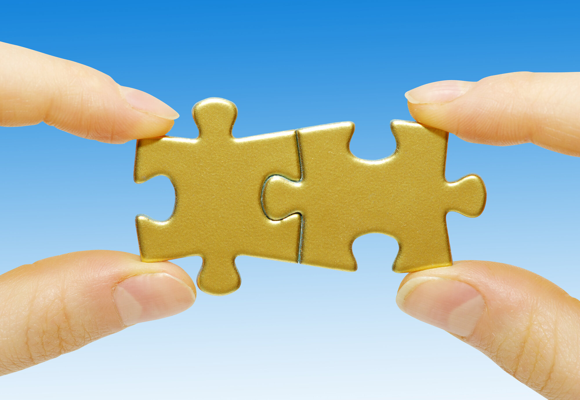 Bildet viser to hender som holder hver sin puslespillbit som er puslet sammen.