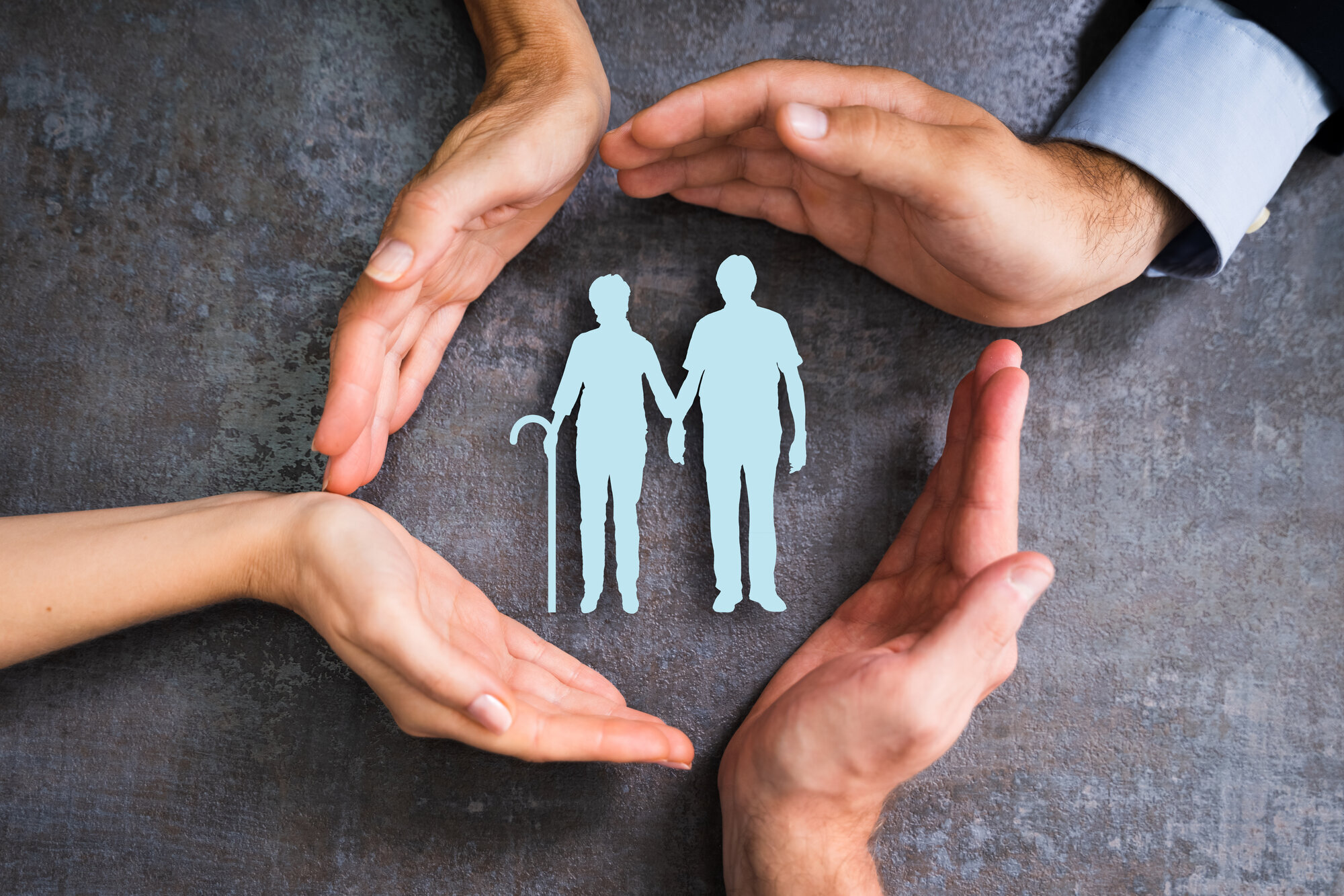 Bildet viser fire hender som verner to gamle mennesker.