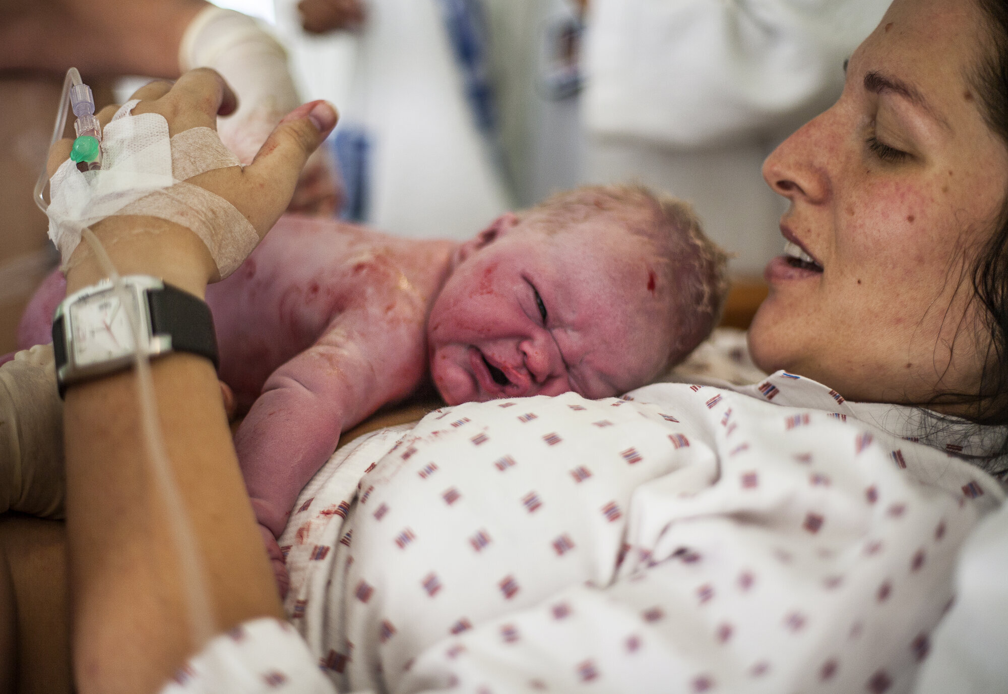 Bildet viser en nyfødt baby som ligger på magen til moren