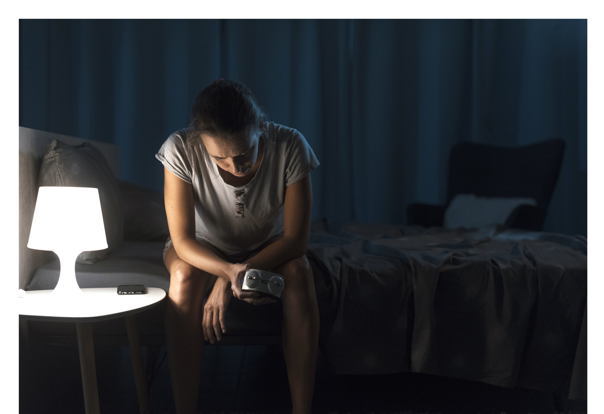 Bildet viser en kvinne som sitter på sengekanten og ikke får sove