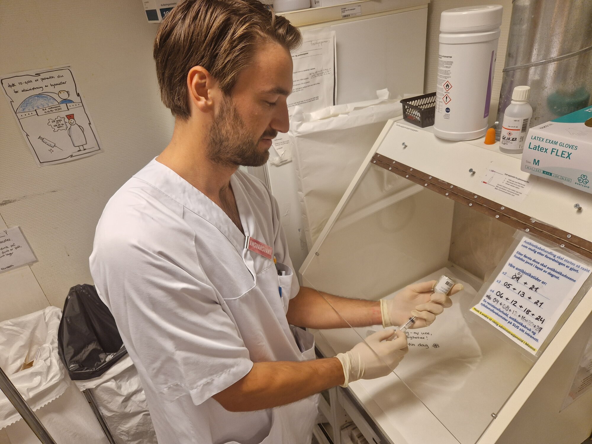 En mannlig sykepleier klargjør en sprøyte med antibiotika.