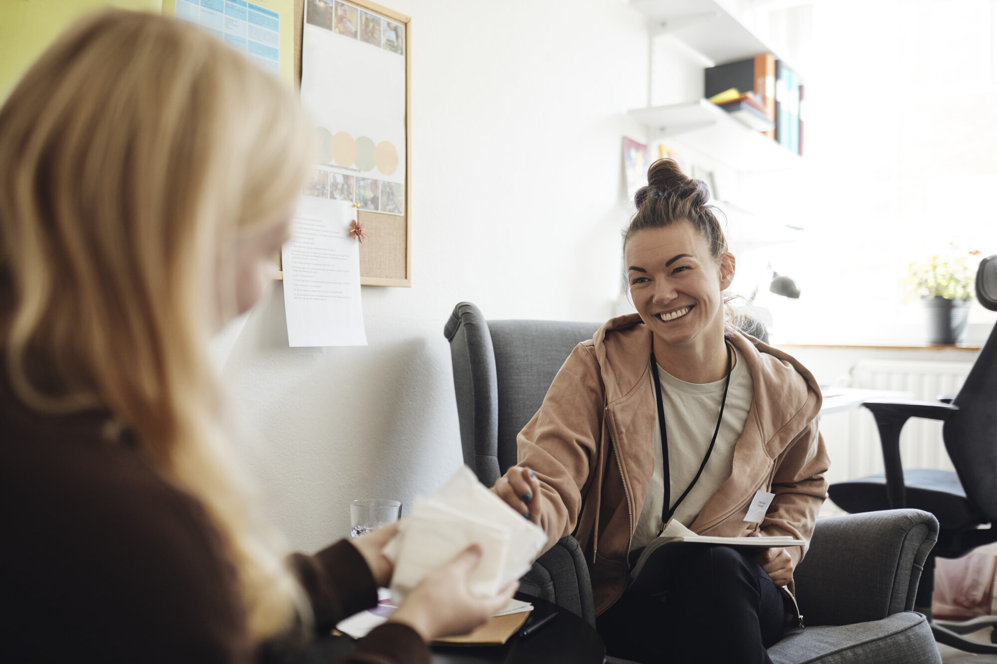 Bildet viser en smilende, kvinnelig helsesykepleier i samtale med en annen kvinne.