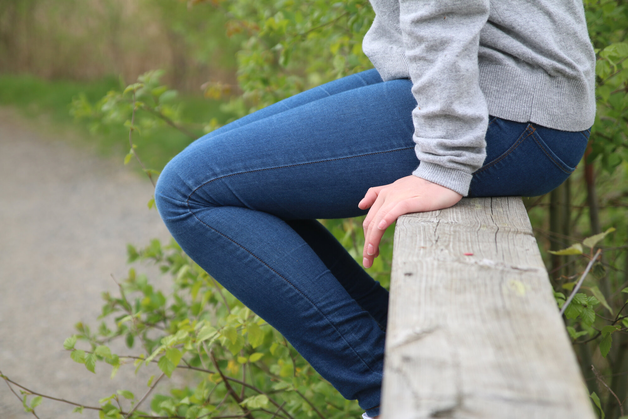 Bildet viser et utsnitt av en jente som sitter på et gelender. 