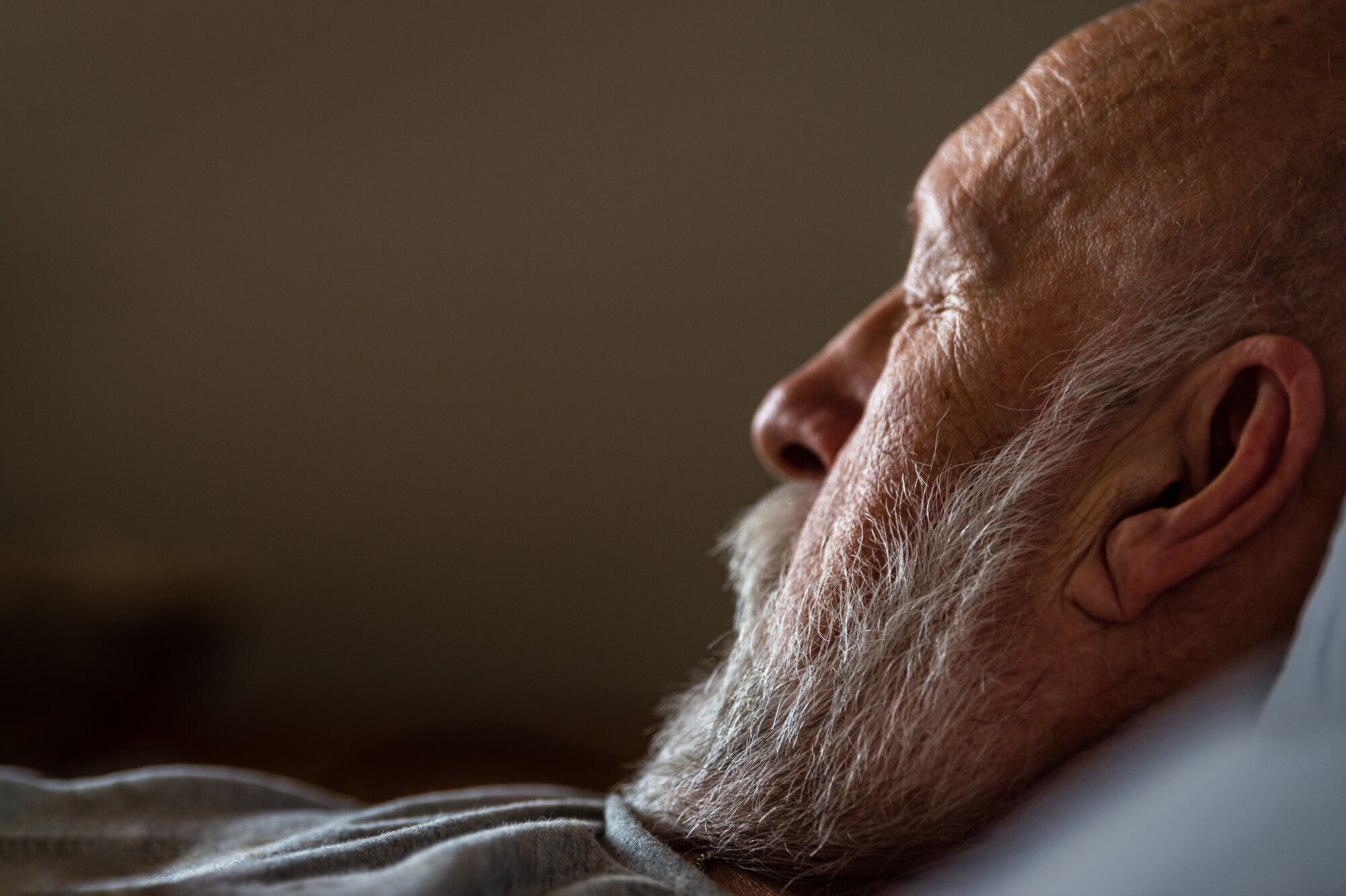 Bildet viser en eldre mann i profil med lukkede øyne. Han ligger i sengen.