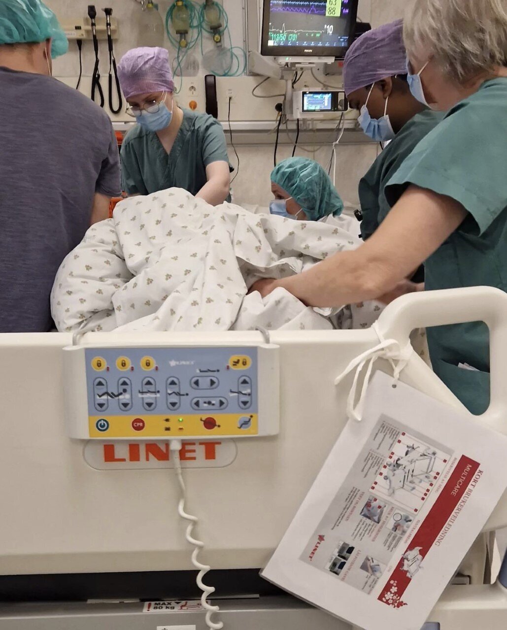 Bildet viser helsepersonell rundt en seng.